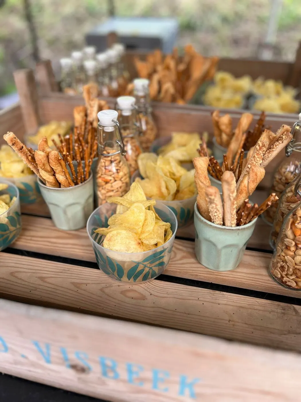 Bekers met chips en soepstengels op een houten krat